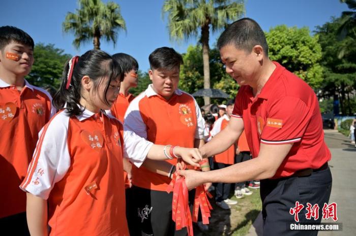 資料圖：廣西華僑實驗高中的教師為高三學子系上紅絲帶，盼望學子高考必勝。 俞靖 攝